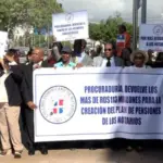 **Cambio de Noticia: Marcha del Colegio Dominicano de Notarios Exige Fondos Retenidos por la Procuraduría** En un acto de reclamo, miembros del Colegio Dominicano de Notarios marcharon hacia la Procuraduría General de la República, exigiendo la entrega de más de 113 millones de pesos que alegan la entidad retiene de forma "ilegal e injustificada", afectando al gremio. La presidenta del Colegio, Laura Sánchez Jiménez, lideró la manifestación, explicando que la entidad busca la aplicación de la Ley 140-15 para asegurar planes de pensiones, ayudas médicas y contar con recursos necesarios para la firma digital. La marcha, iniciada en la esquina de las avenidas Jiménez Moya con Correa y Cidrón, concluyó en el edificio que alberga la Procuraduría. Sánchez Jiménez sostuvo que la Procuraduría dejó de pagar al Colegio por la transferencia de 130 pesos por cada acto notarial certificado desde la entrada en vigor de la Ley 140-15 en agosto de 2015. Durante este periodo, según la presidenta, la Procuraduría no ha acreditado completamente los montos correspondientes al Colegio, acusándola de causar daños materiales y morales al afectar las labores de la entidad. Señaló que la Procuraduría ha percibido cerca de tres mil millones de pesos por la aplicación del recibo notarial, alegando que la entidad debería cobrar 130 pesos por cada acto notarial según la Ley 140-15 del Notariado, pero está cobrando 700 pesos, entregando solo 80 pesos al Colegio. Además, advirtió que el Colegio Dominicano de Notarios no permitirá transgresiones ni actuaciones impropias por parte de la Procuraduría ni de ningún otro órgano, público o privado, en detrimento de las responsabilidades reservadas por la ley. Manifestó que la disposición de la Procuraduría de aumentar el monto del recibo de manera desproporcionada en su beneficio propio, no del Colegio de Notarios y en perjuicio de la ciudadanía, es una aplicación impropia, careciendo de competencia para ello, según lo establecido por la Ley No. 140-15 del Notariado