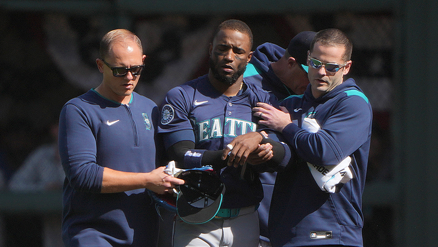 Dominicano Víctor Robles de los Marineros de Seattle es asistido para salir del campo de juego luego de lesionarse en una jugada defensiva en el jardín derecho.