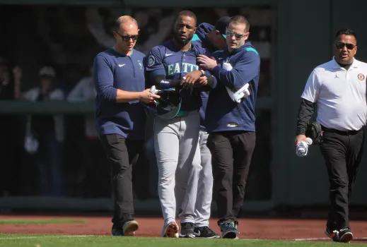 Dominicano Víctor Robles de los Marineros de Seattle es asistido para salir del campo de juego luego de lesionarse en una jugada defensiva en el jardín derecho.