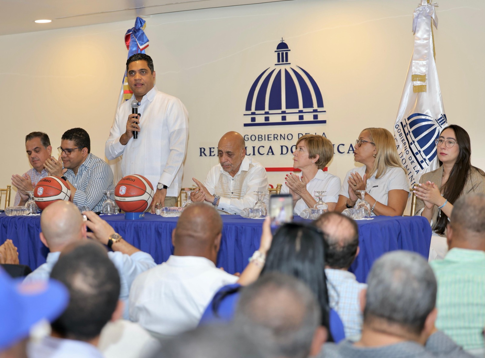 ministro de Deportes Kelvin Cruz se dirige a los presentes para anunciar el respaldo económico que dará el Ministerio de Deportes para el 9no torneo de la LNBF. Figuran, desde la izquierda, Antonio Mir, Rafael Uribe y Fernando Teruel, presidentes de la LNB, Fedombal y LNBF, respectivamente, Pilar Báez, Minerva Doñé y Nicole Feliz Bernard.