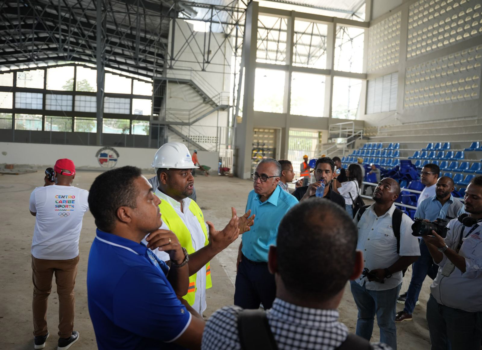 José P. Monegro y Luisín Mejía, presidentes del Comité Organizador y Centro Caribe Sports, respectivamente, escuchan junto a los periodistas  explicaciones del ingeniero Ángel Beltré, del Ministerio de la Vivienda y Edificaciones en el Palacio del Voleibol, Gioriver Arias.
