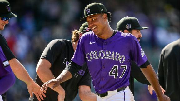 Juan Mejía lanzador dominicano, de los Rockies de Colorado, sonríe al saludar a sus compañeros al finalizar el partido.
