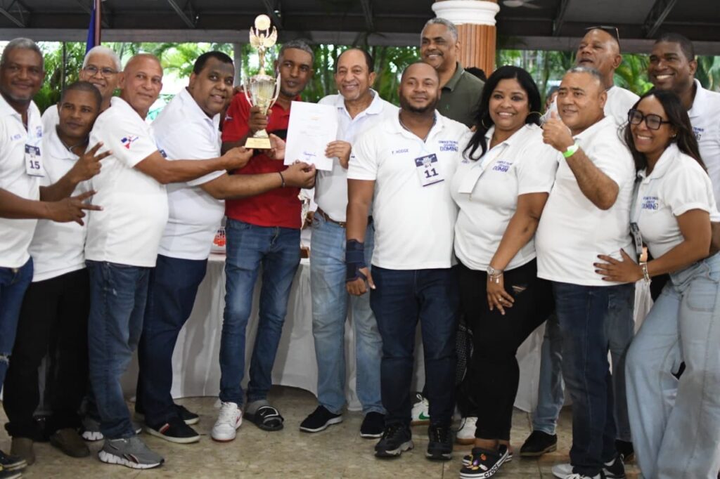 Jorge Ramírez, presidente del club Los Prados, entrega la Copa Restauración de Dominó al equipo campeón del Grupo 2, club Deportivo La Fe, que reciben sus integrantes.