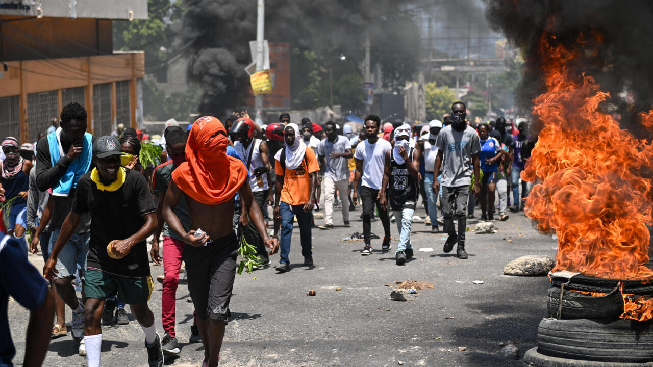 Decenas de personas caminan mientras arden neumáticos durante una protesta contra la inseguridad. Cerca de la residencia oficial del primer ministro, en Puerto Príncipe, Haití, el 7 de agosto de 2023. AFP/Richard Pierrin