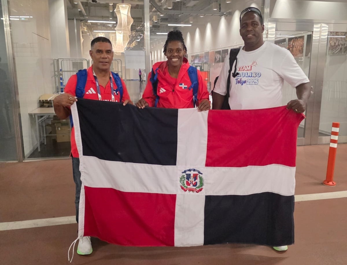 El presidente de la Federación de Atletismo, ingeniero Alexis Peguero, con la bandera dominicana en manos, junto a la atleta, Marileidy Paulino y su entrenador, Yassen Pérez, luego de la carrera final.