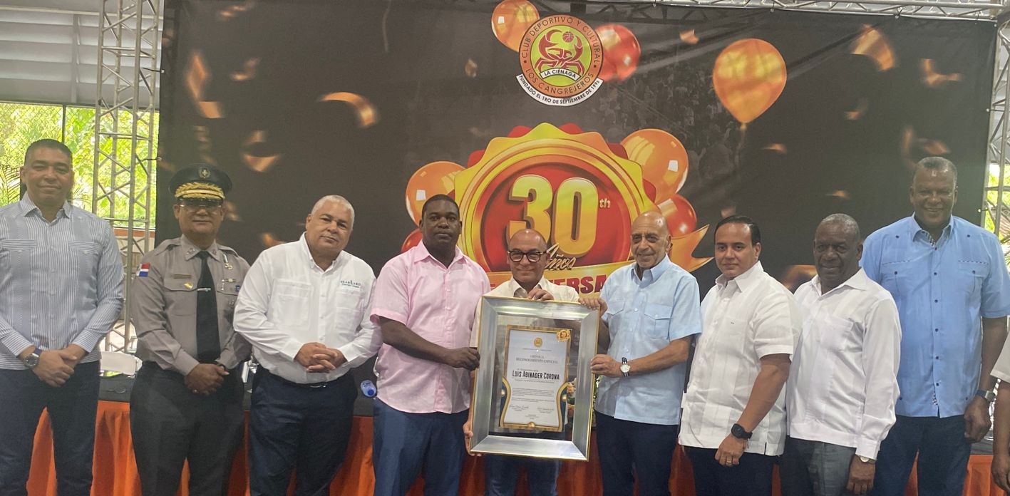 Edwin Castillo (Tatico), presidente del Club La Ciénaga, entrega una placa de reconocimiento a Rolfis Rojas, en representación del presidente Luis Abinader Corona. Le acompañan, desde la izquierda, Junior Páez, Jacobo Mateo Moquete, Fernando Geraldino, Fernando Teruel, Elvis Duarte, Leopoldo Portes y Evaristo Pérez.