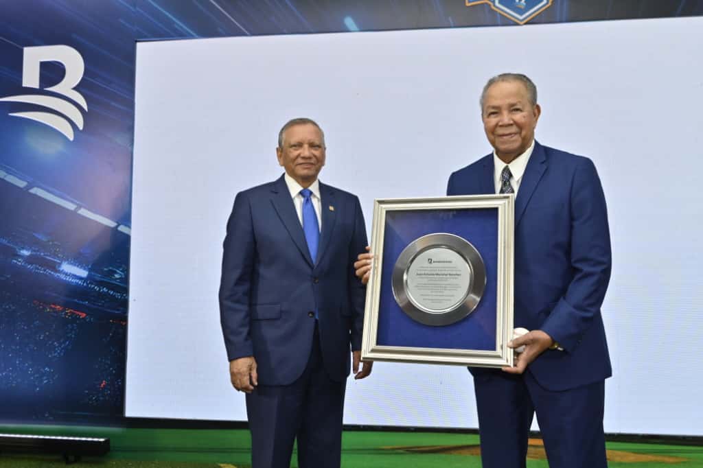 Juan marichal recibe placa de reconocimiento por la dedicatoria del próximo torneo de béisbol invernal de manos del presidente ejecutivo del Banco de Reservas Leonardo Aguilera.