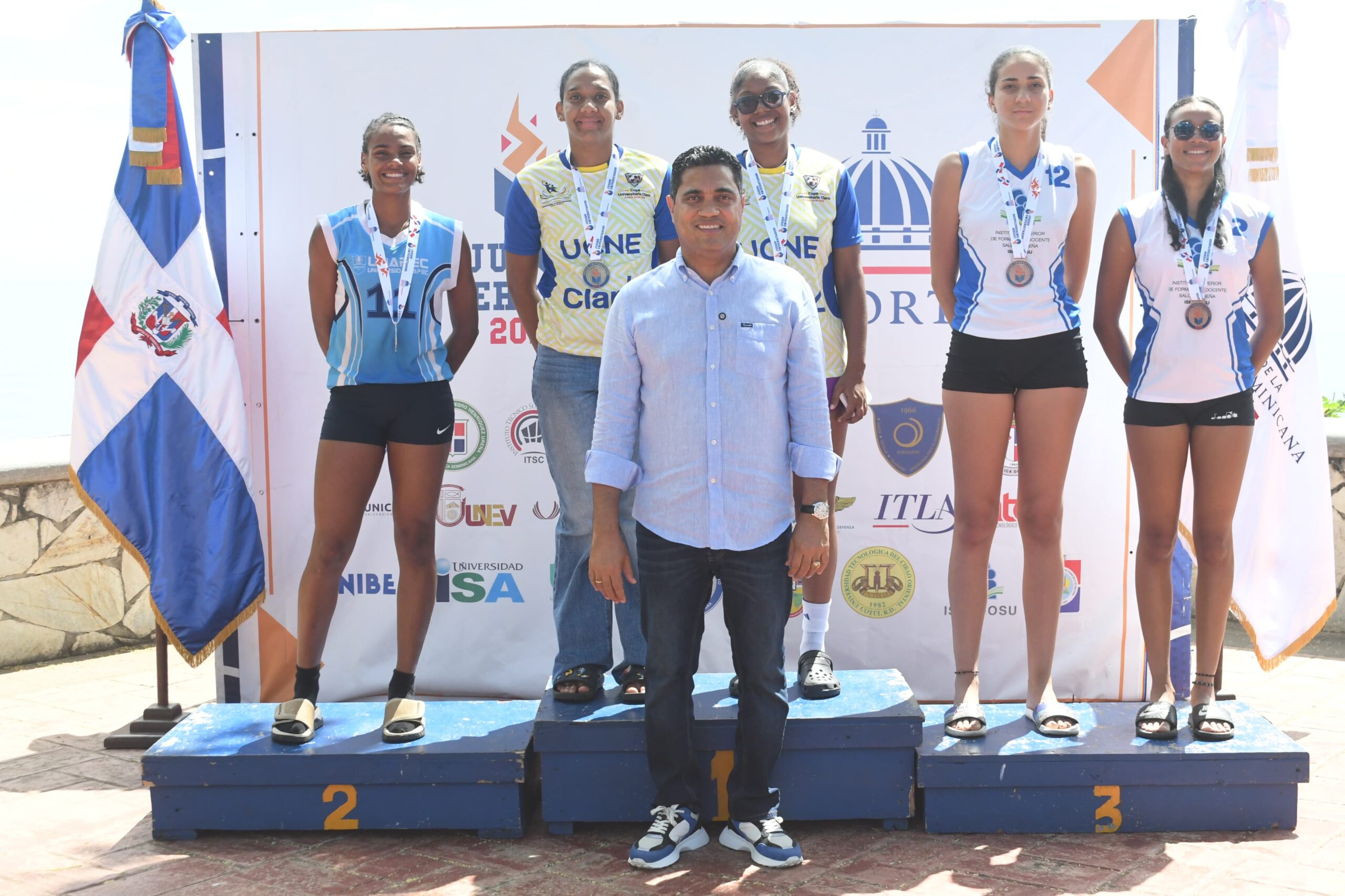El ministro de Deportes, Kelvin Cruz, junto a las duplas medallistas del voleibol de playa femenino de los Juegos Deportivos Universitarios. UCNE ganó oro, UNAPEC plata y UNICARIBE bronce.