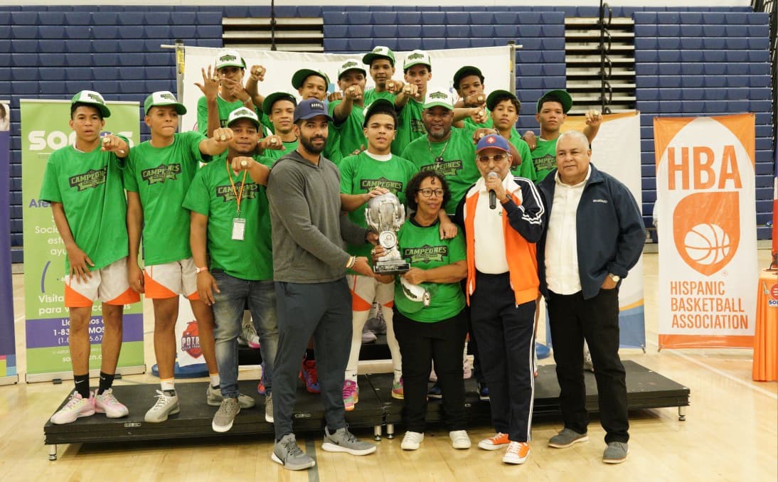 Alex Damirón, ejecutivo de Hispanic Basketball Association (HBA), le entrega la copa de campeón a Amerfis Rijo, delegada del club El Edén de Nagua. A la derecha, Manolito Prince, presidente de la HBA, y Fernando Geraldino, de la empresa Seaboard “Energía Limpia”.