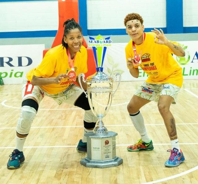 Las jugadoras Sugey Monsac y Jennifer Jiménez, de las Águilas de Guachupita, junto a la Copa Seaboard que conquistaron ante San Carlos.