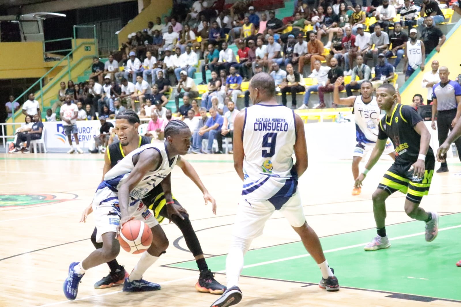 Daylin Thomas, de Consuelo, avanza con el balón ante la defensa de Edison Montilla, de Miramar, y el bloqueo de Dreslin Richardson (9). A la derecha, Danny Solano (8).