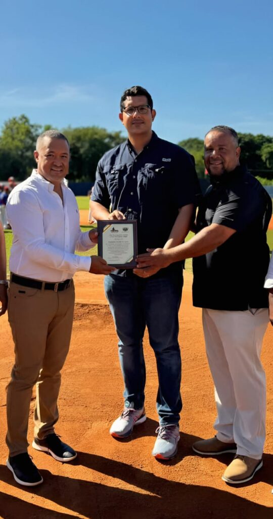 Luis Ramírez y Cristian Pimentel entregan la placa de reconocimiento al señor Ricardo Núñez, representante de la Fundación Huellas de Apoyo