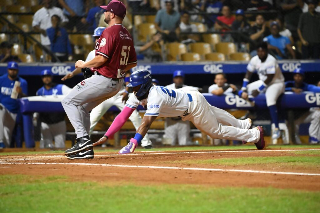 Así anota el Licey su primera carrera, con lanzamiento desviado y corrido de bases agresivo deslizándose Mel Rojas Jr de cabeza en el plato.