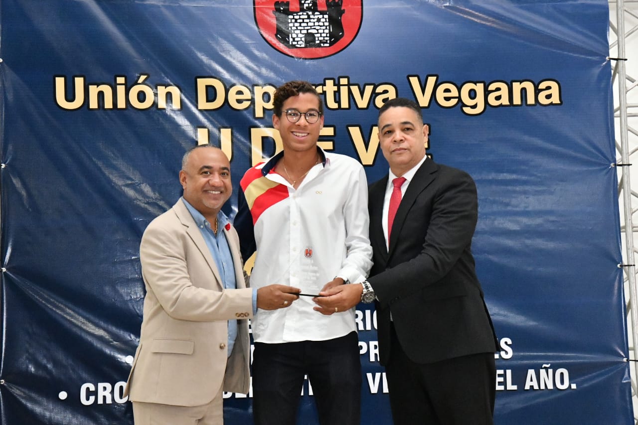 Enmanuel Muñoz Veras recibe su galardón como el mejor en tenis de campo en la premiación de la UDEVE, de Danny Holguín y el vicealmirante (r) José Roberto Muñoz Monción.