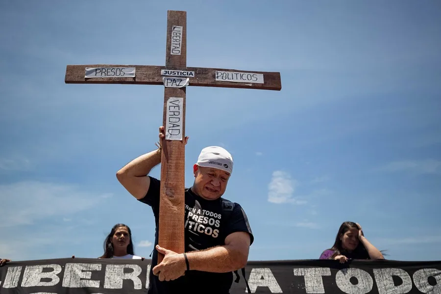 Un hombre sostiene una cruz durante una procesión silenciosa hasta la Nunciatura Apostólica este viernes, en Caracas (Venezuela). EFE