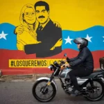 Una persona transita frente a un mural del presidente de Venezuela, Nicolás Maduro, y su esposa, Cilia Flores, este lunes, en Caracas (Venezuela). EFE