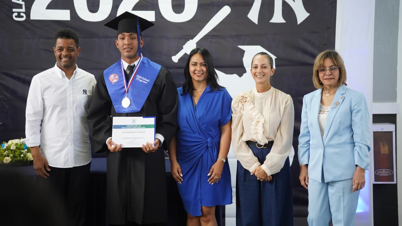 Joel Lithgow, director de la academia de los Yankees de Nueva York en la República Dominicana, Melissa Hernández, aistente de desarrollo de jugadores y Providencia Fernández, ejecutiva de FUNDAPEC, reconocen a uno de los prospectos que recibió su diploma de secundaria. 