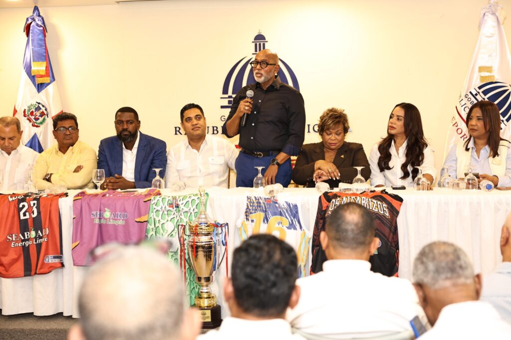 Ángel De la Cruz, al frente del Comité Organizador del TBS Santo Domingo 2026, ofrece declaraciones ante el público presente, acompañado de, izquierda a derecha, Garibaldi Bautista, Junior Santos, William Cabral Lugo, el ministro de Deportes Kelvin Cruz, Lucrecia Santana, Betty Gerónimo y Anny Mambrú.
