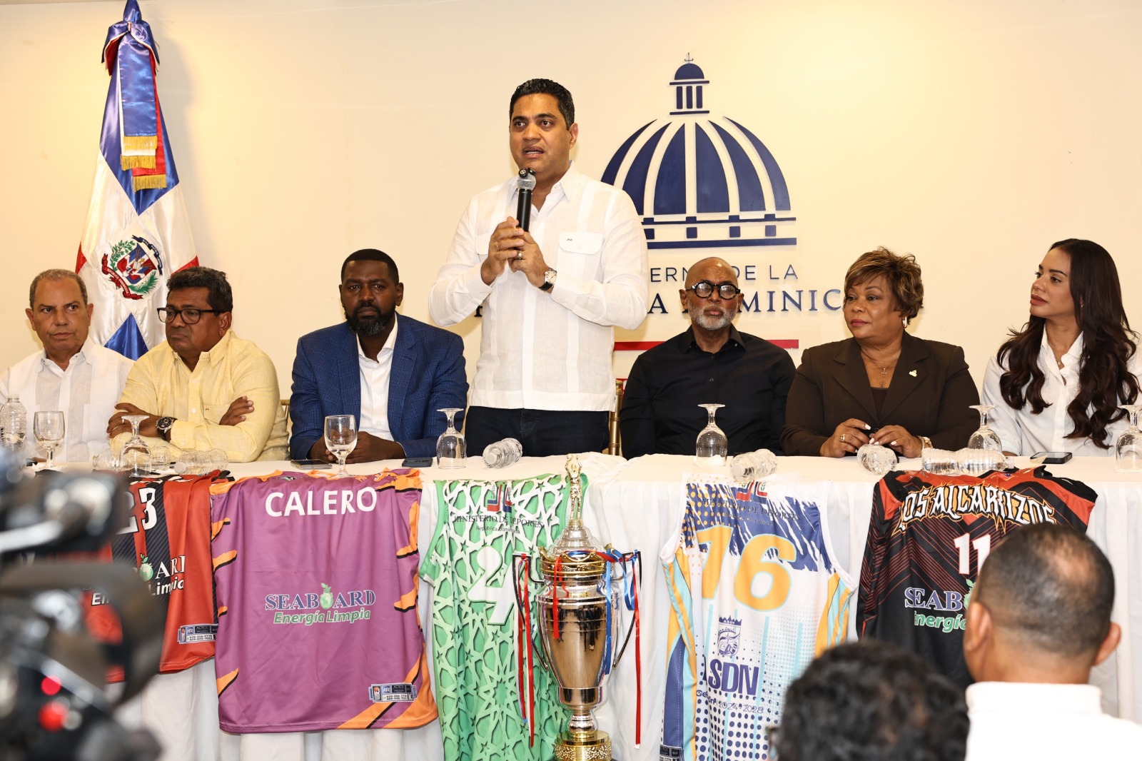 El ministro de Deportes Kelvin Cruz anuncia el aporte de dos millones de pesos para el TBS Santo Domingo 2026, junto a -de izquierda a derecha-, Garibaldi Bautista, Junior Santos, William Cabral Lugo, Ángel De la Cruz, Lucrecia Santana y Betty Gerónimo.