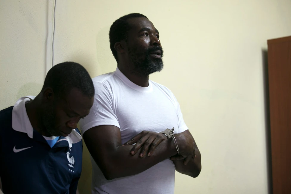 El exdiputado Arnel Belizaire, derecha, aparece esposado al ser presentado por la Policía Nacional ante la prensa junto con otros hombres