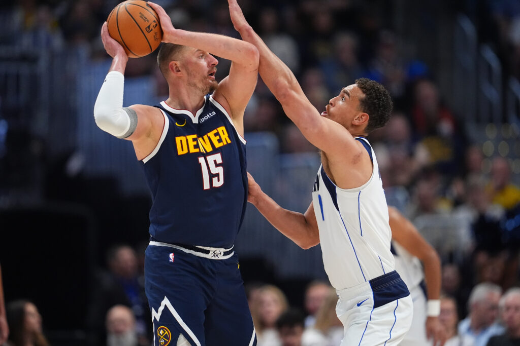 El centro Nikola Jokić de Denver Nuggets, busca como pasar el balón ante la defensa de Dwight Powell de los Dallas Mavericks. (AP Foto/David Zalubowski)