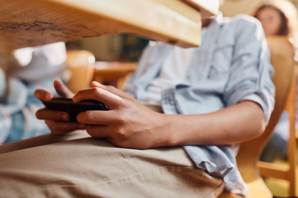 Un estudiante usa el celular a escondidas en medio de la clase