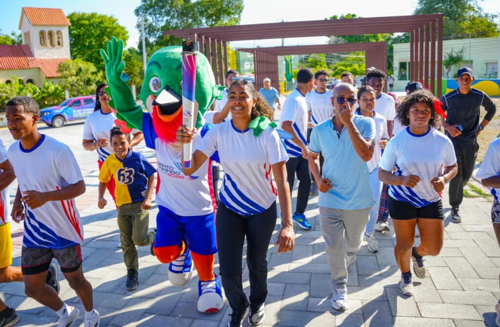 La joven atleta de voleibol, Yarianna Torres, porta la antorcha centroamericana y del Caribe, en el recorrido de Neiba.