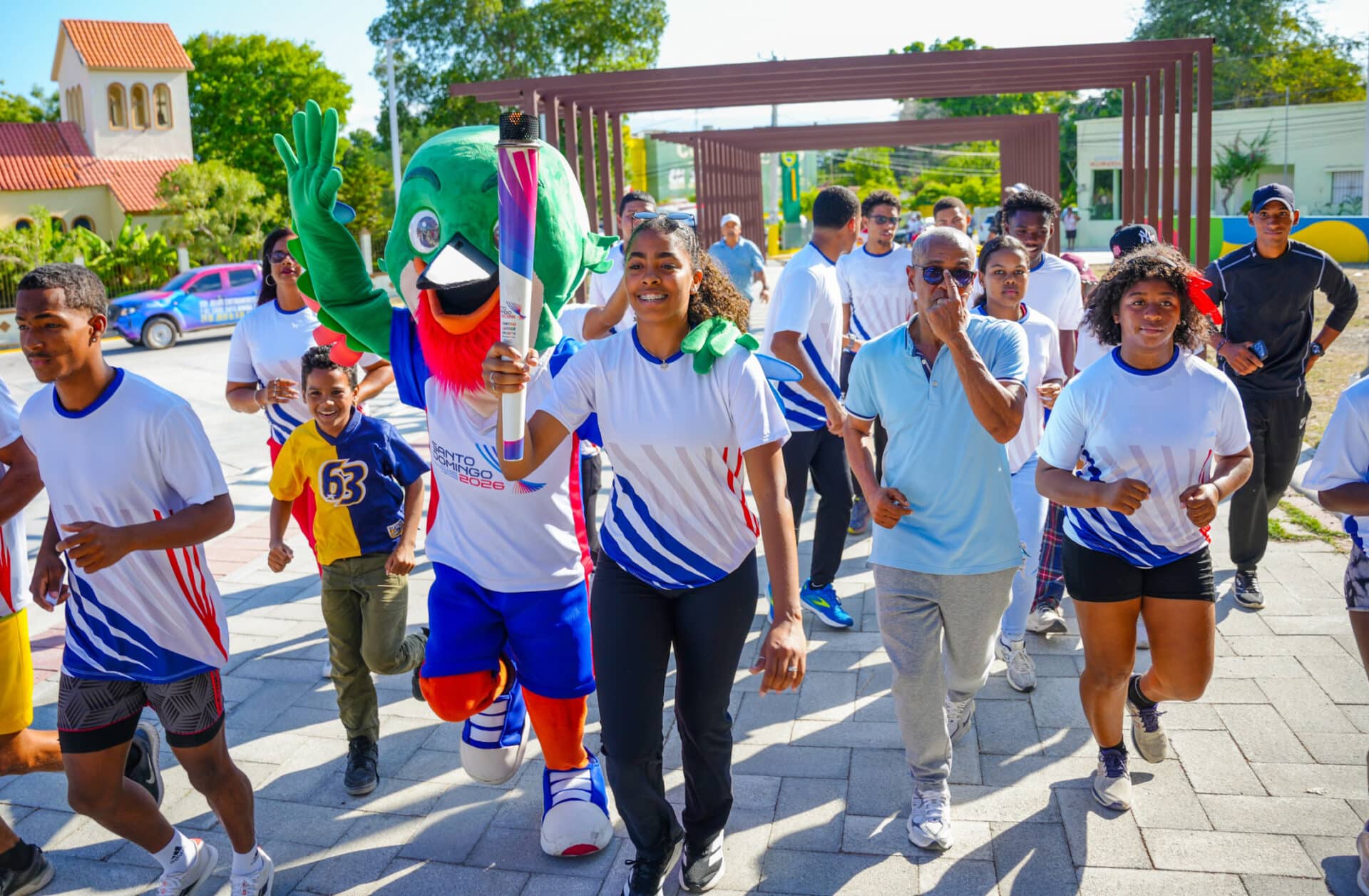 La joven atleta de voleibol, Yarianna Torres, porta la antorcha centroamericana y del Caribe, en el recorrido de Neiba.