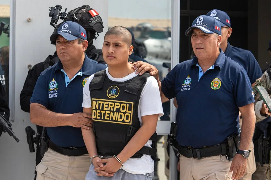 Fotografía de agentes de Interpol trasladando al peruano Tony Janzzen Valverde Victoriano (c), conocido como Pequeño J, para ser extraditado a Argentina, en Callao (Perú). EFE/ Renato Pajuelo.