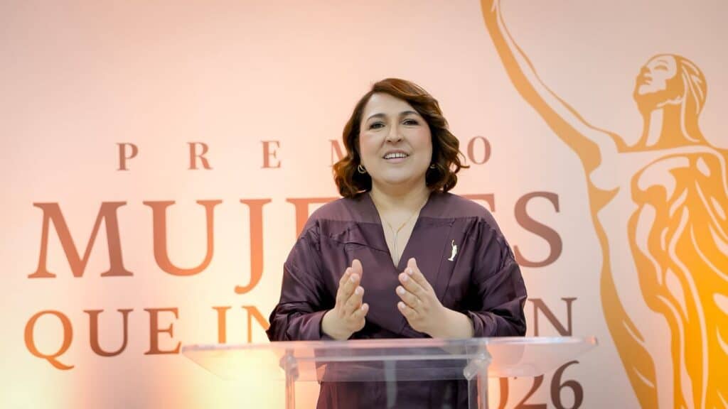 Reconocida mujer en evento de premios, recibiendo galardón por su trayectoria profesional en la indu.