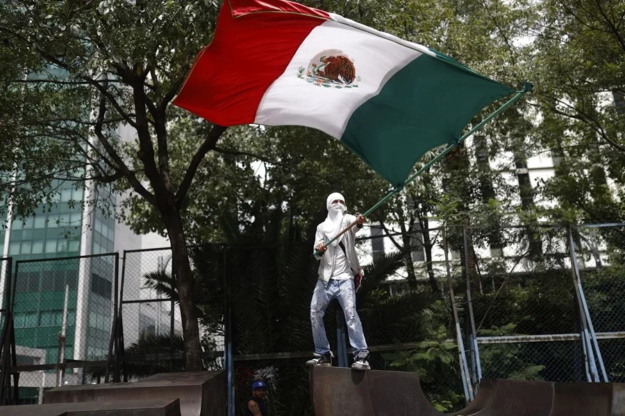 Una persona sosteniendo una bandera de México durante una protesta.