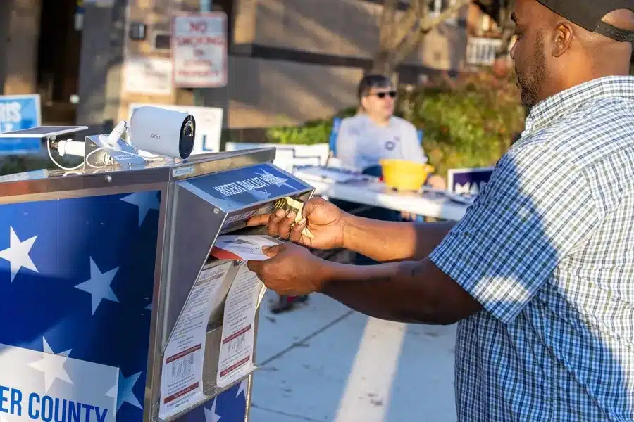 Una persona depositando su voto por correo en una urna designada en Estados Unidos.