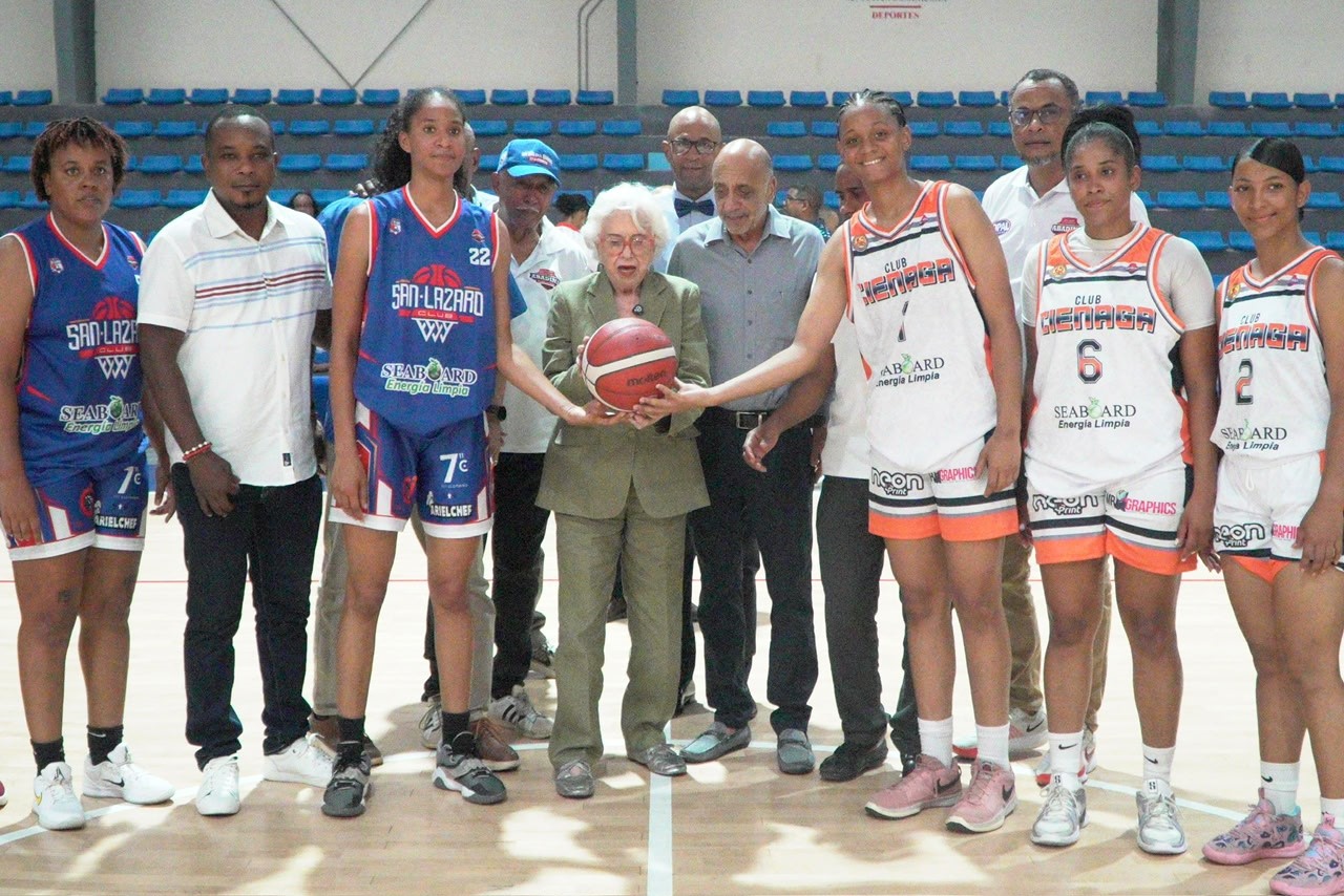 Doña Milagros Ortiz Bosch realiza el saque de honor, junto a las autoridades de Abadina y las jugadoras de los clubes San Lázaro y La Ciénaga.