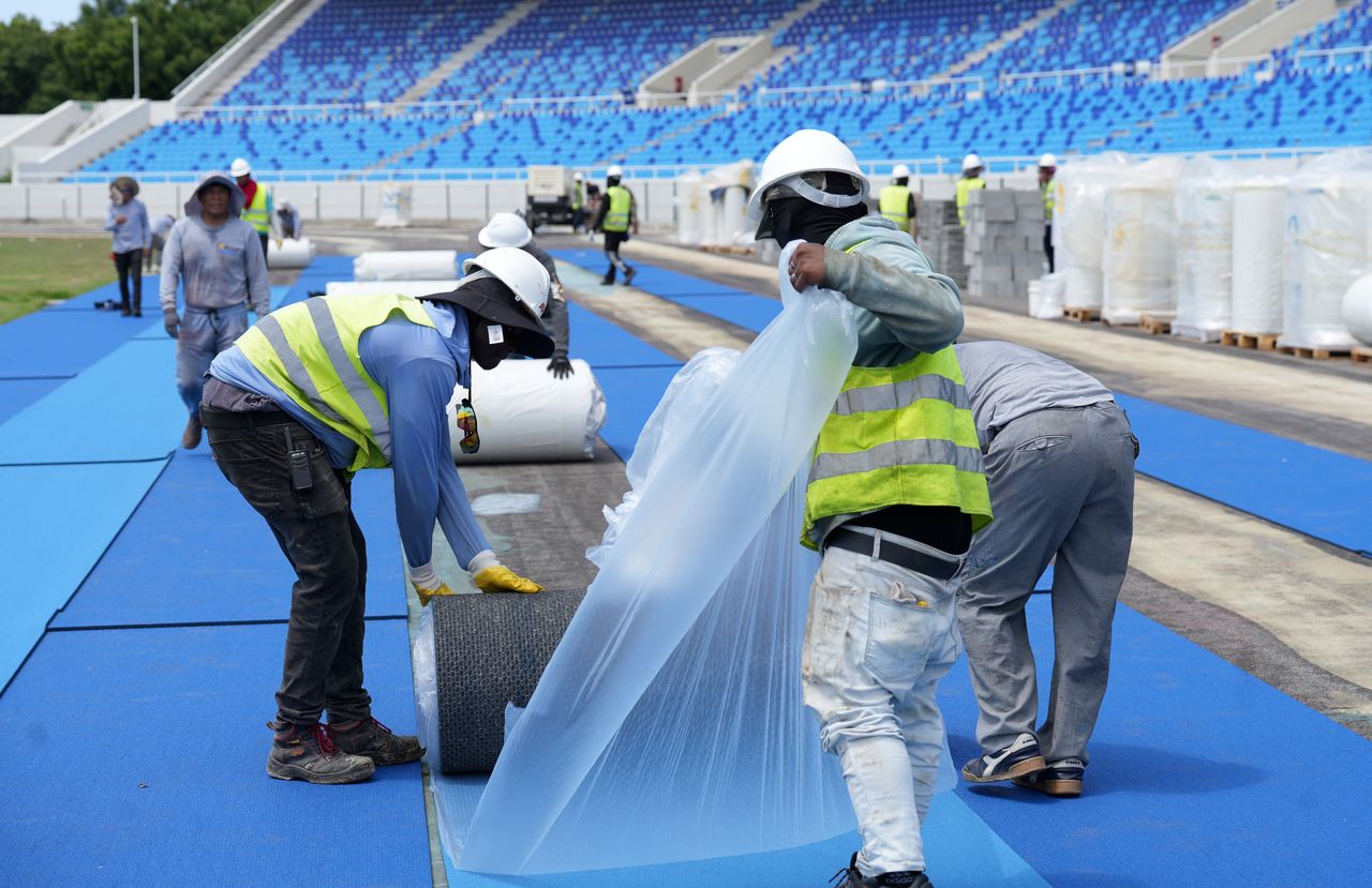 Obreros trabajan en la colocación del sintético de la nueva pista del estadio olímpico Félix Sánchez, la primera con tecnología de punta en América.