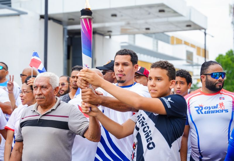 El exvelocista Porfirio –Popo- Veras Mercedes camina con la antorcha de los Juegos Centroamericanos y del Caribe Santo Domingo 2026 durante su recorrido por La Vega.