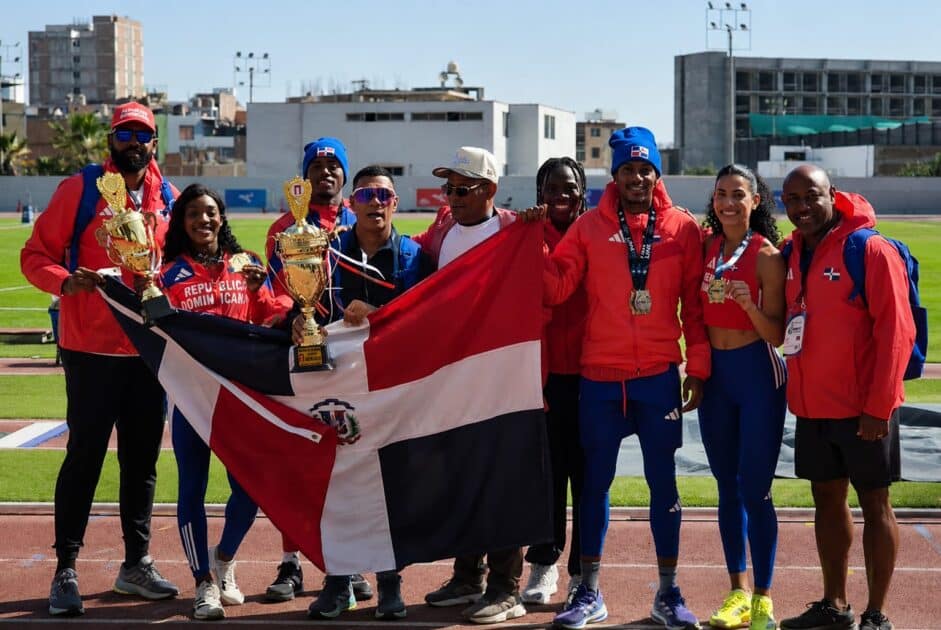 El presidente de la Federación de Atletismo, ingeniero Alexis Peguero, junto a sus atletas con la bandera tricolor y el trofeo de tercer lugar en el Campeonato Iberoamericano.