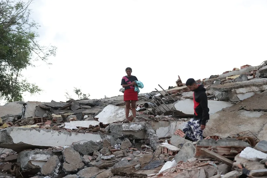 Residentes caminan entre los escombros de varios edificios de apartamentos dañados por los terremotos, en Catia la Mar, Venezuela.