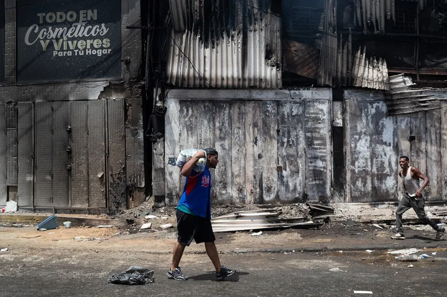 Una persona carga un paquete este viernes, durante un saqueo a un establecimiento comercial, en Catia La Mar (Venezuela). EFE/ Ronald Peña R