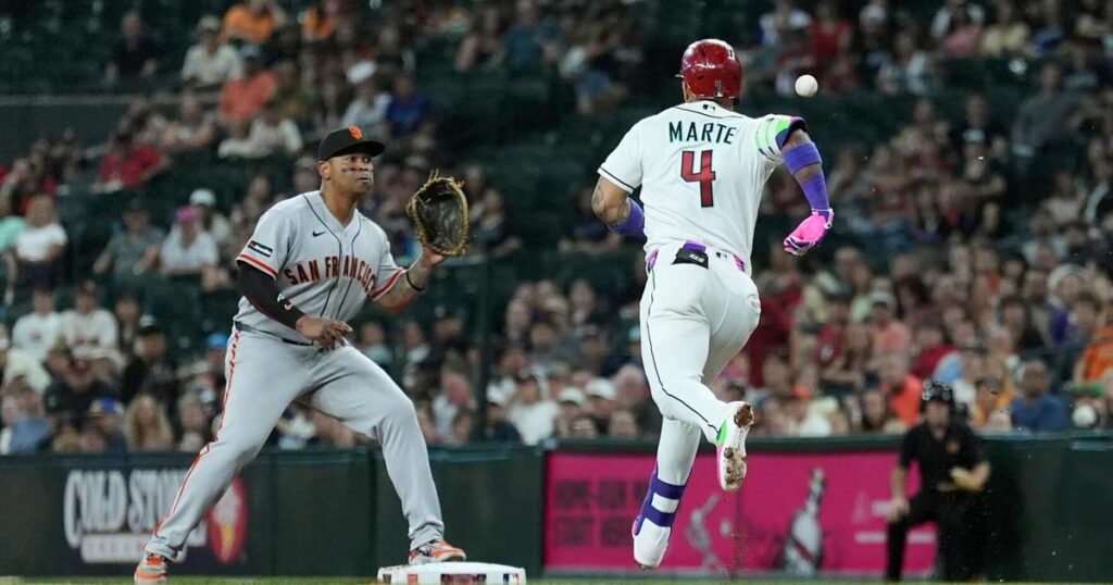 Devers en primera espera la bola mientras que Ketel Marte trata de llegar a salvo